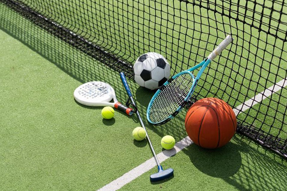 Basketball, football, rackets, and tennis balls on a pitch.